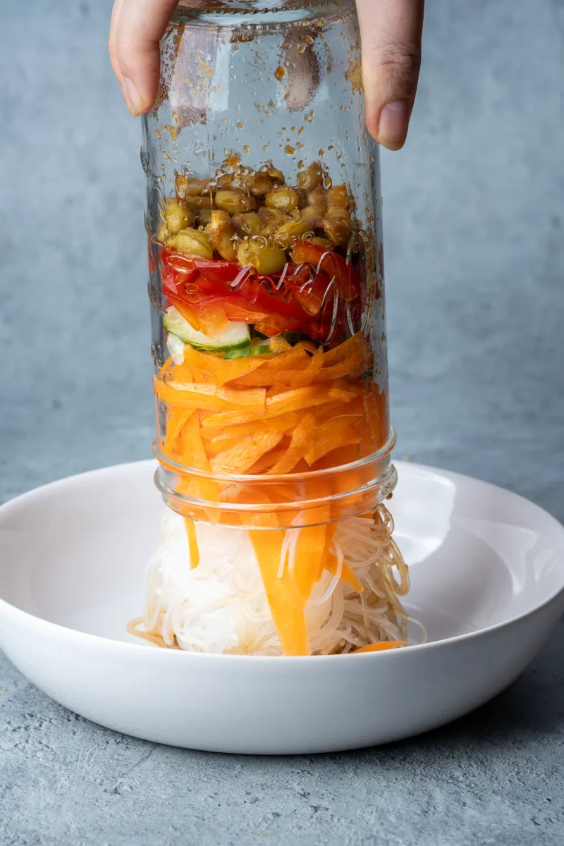 Glasnudelsalat im Glas – perfekt für Meal Prep 2 Ein Glas mit Glasnudelsalat wird auf einen Teller gekippt