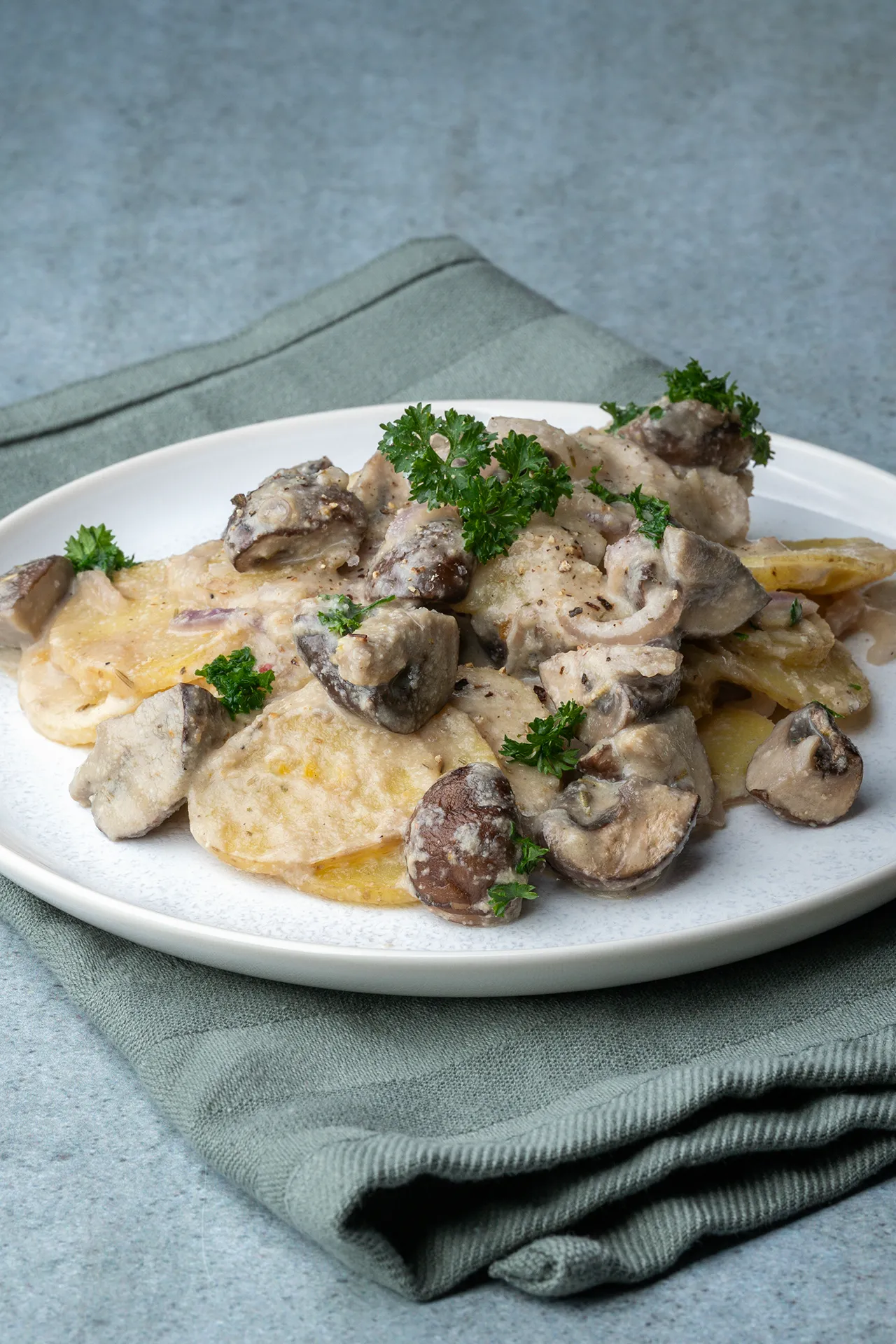 Kartoffel-Champignon-Auflauf in cremiger Knoblauchsoße 3 Veganer Kartoffel-Champignon-Auflauf ohne Sahne auf einem hellen Teller