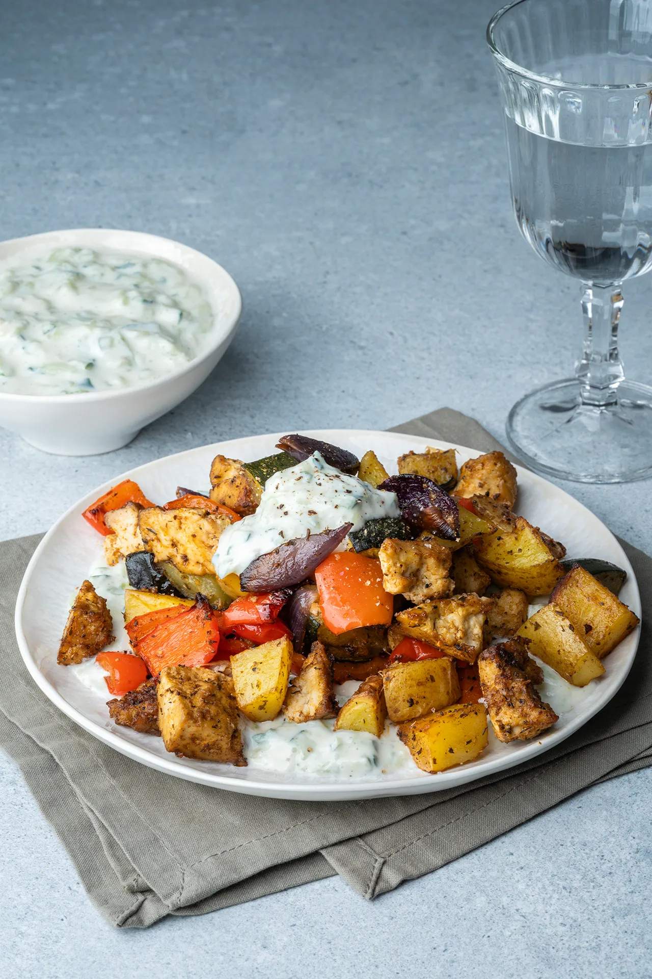 veganes Gyros Wurfblech mit Zaziki und einem Glas Wasser