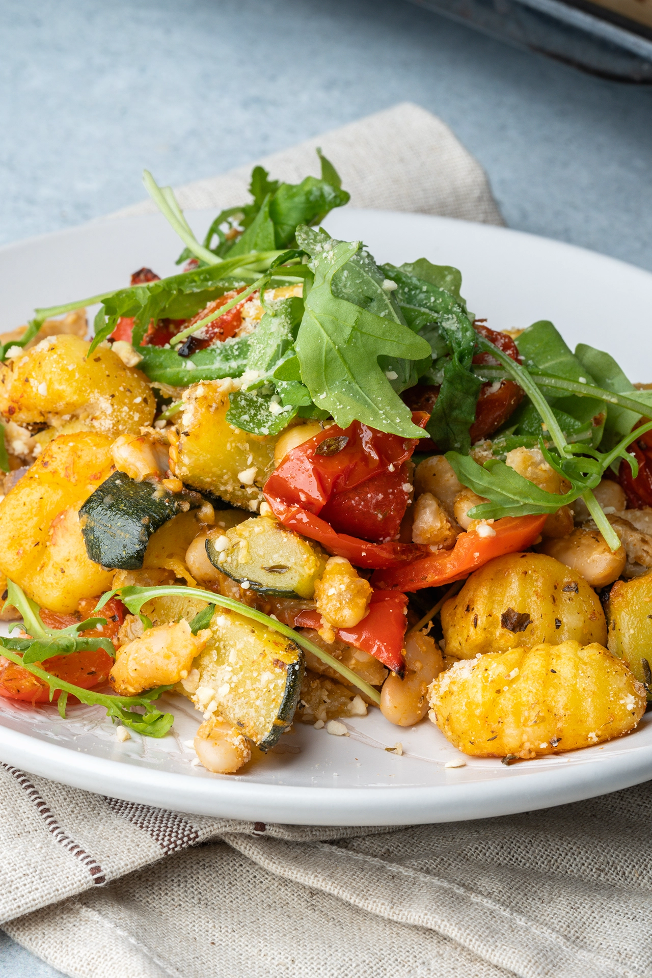 mediterranes Gnocchiblech mit Rucola und veganem Parmesan auf einem Teller