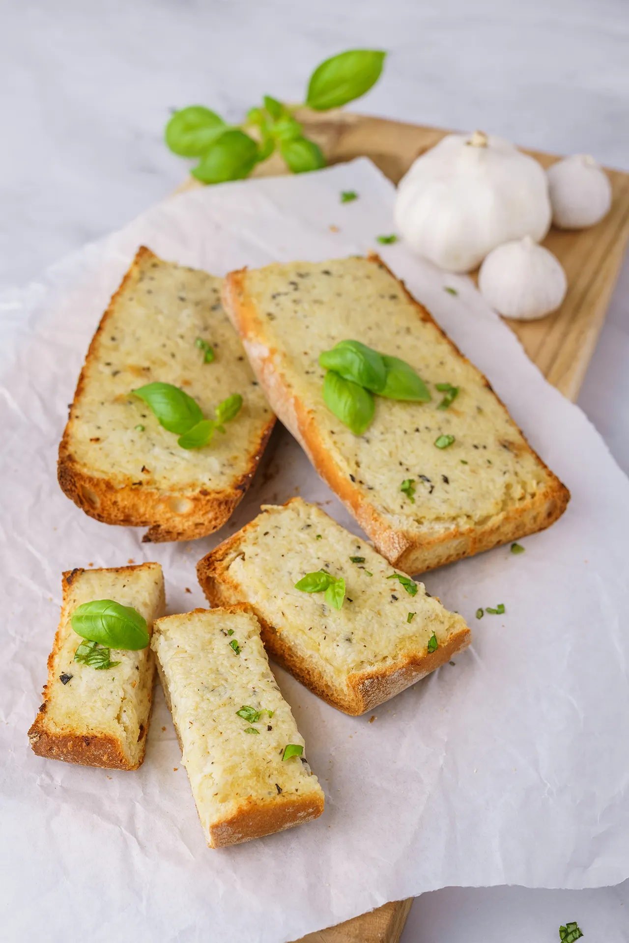 veganes Knoblauch-Mozzarella-Baguette mit Bsilikum auf weißem Backpapier