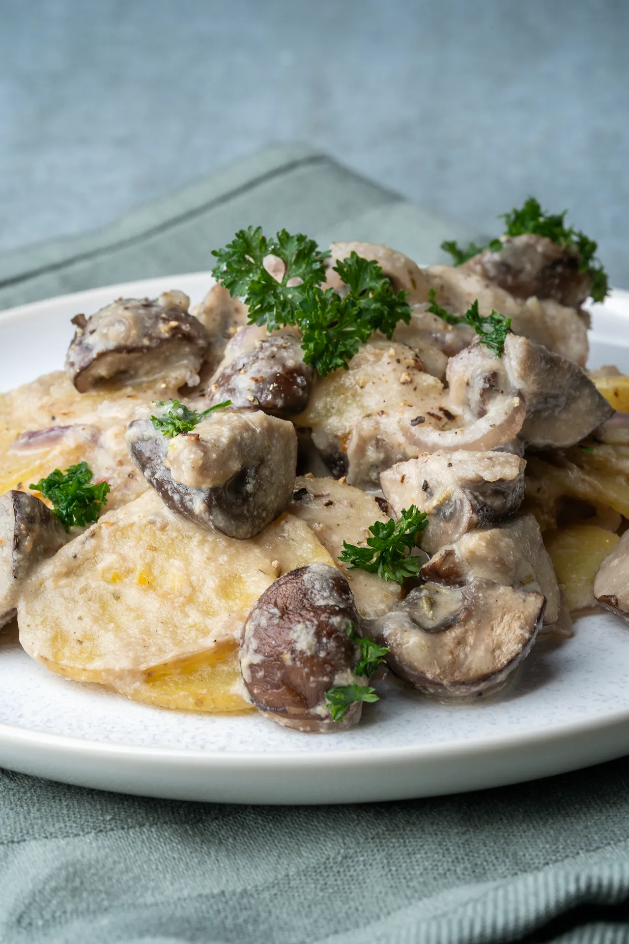 Kartoffel-Champignon-Auflauf in cremiger Knoblauchsoße 1 Veganer Kartoffel-Champignon-Auflauf auf einem hellen Teller