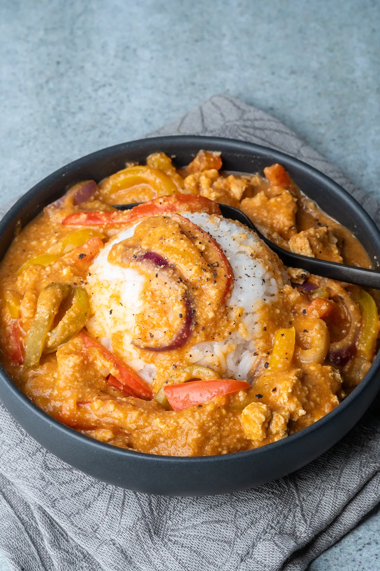 Veganes Paprika-Sahne-Hähnchen mit Tofu – ganz ohne Sahne 3 Veganes Paprika-Sahne-Hähnchen in einer schwarzen Schale mit Reis